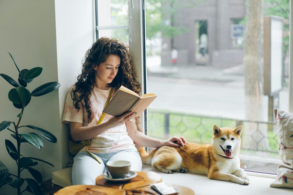 A lady reading a book with her dog. Featured Image 00123